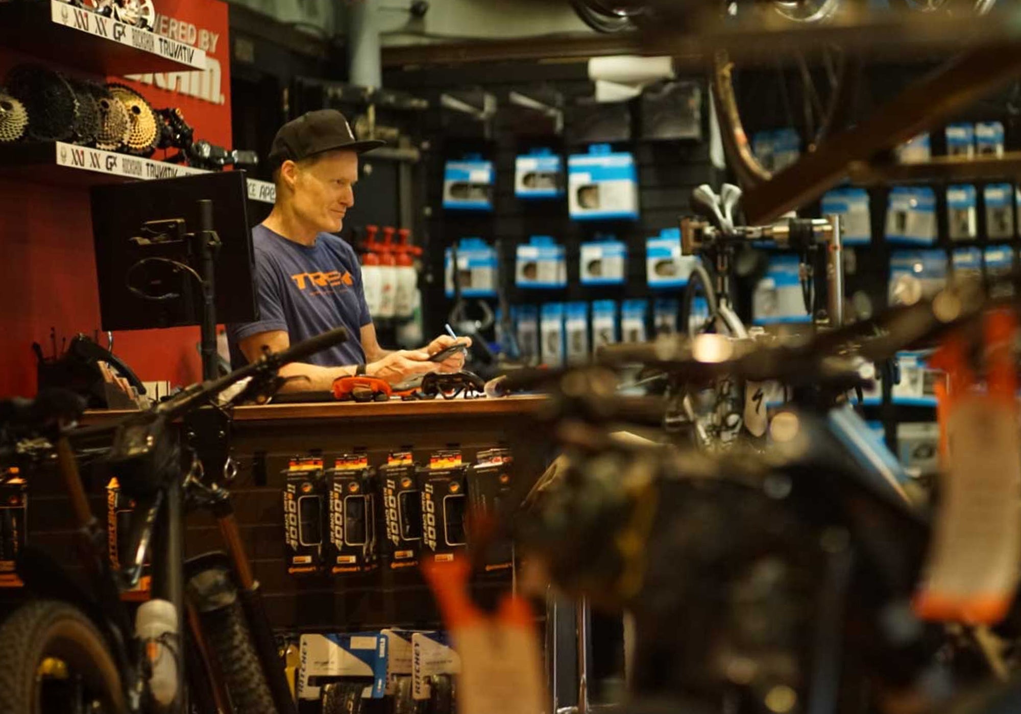 Man working in a bike shop with shelves and products in the background